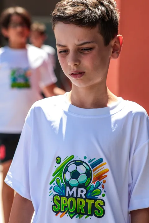Menino de cabeça baixa com a camiseta branca da MR Sports em primeiro plano