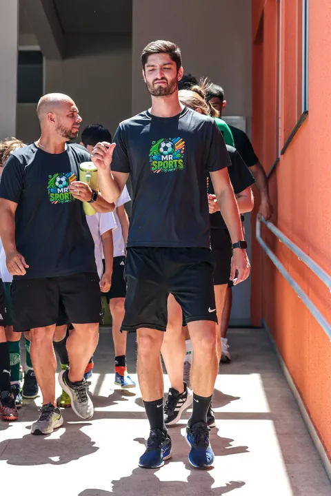 Dois professores de camiseta preta da MR Sports caminham entre os alunos
