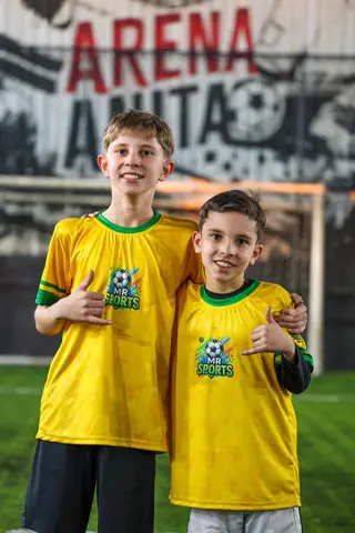 Dois meninos abraçados sorriem com a camiseta amarela da MR Sports