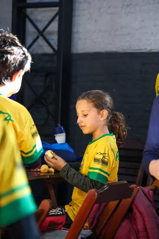 Menina com a camiseta da MR Sports na mesa durante a hora do lanche