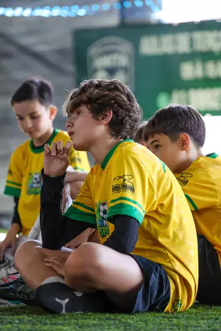 Crianças sentadas no gramado sintético conversam durante a pausa